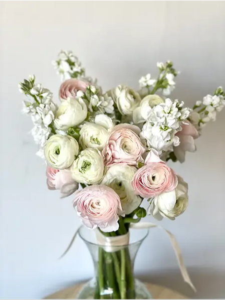 Bouquet with delicate pink and white ranunculi in a transparent vase