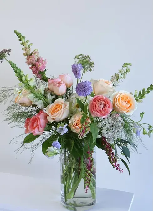 A delicate bouquet of pink and white roses and other seasonal flowers