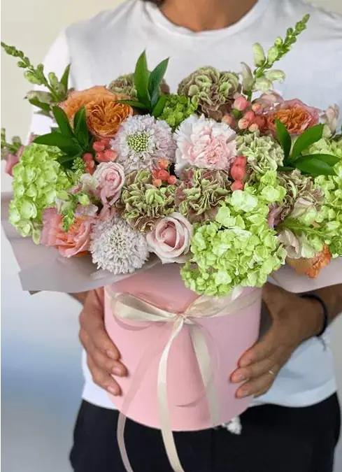 Bouquet of pink and green hydrangeas, roses and other flowers, packed in a pink box