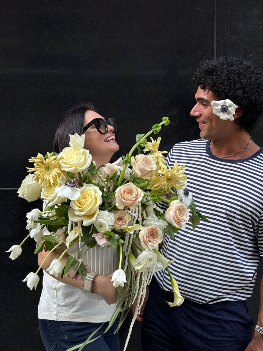 Novapetal cofounders Olga and Anthony Sheppard carrying a large cream and yellow arrangement of garden roses, dahlias, anemones and calla lilies