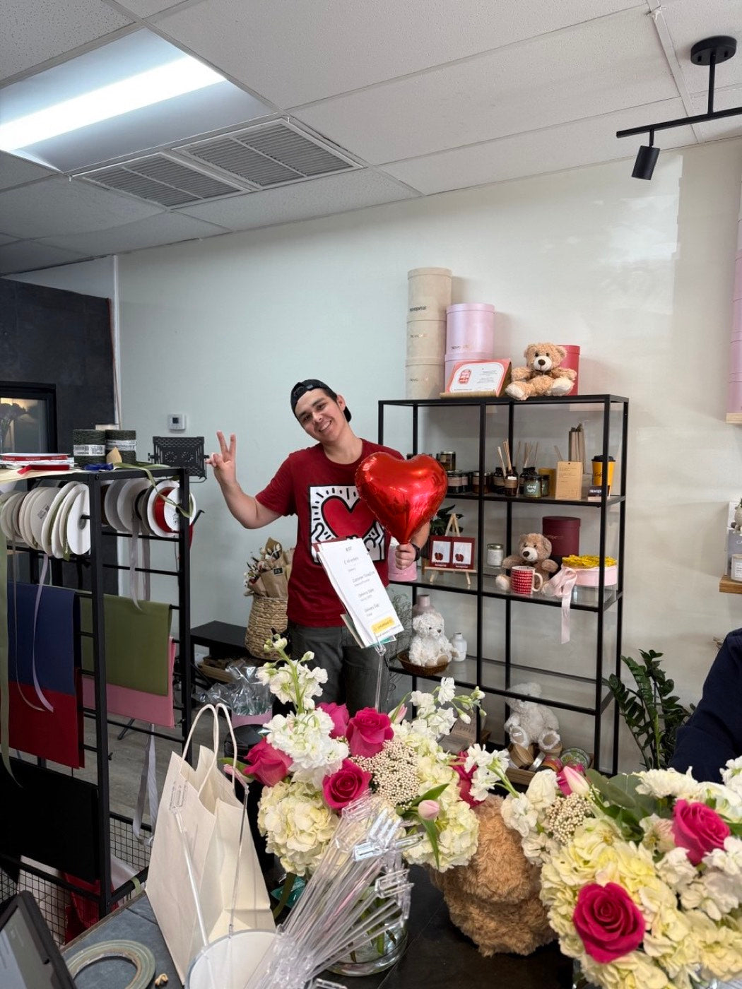 A Novapetal florist at the bench in the Phoenix studio, surrounded by ribbon spools, finished arrangements and gift shelves