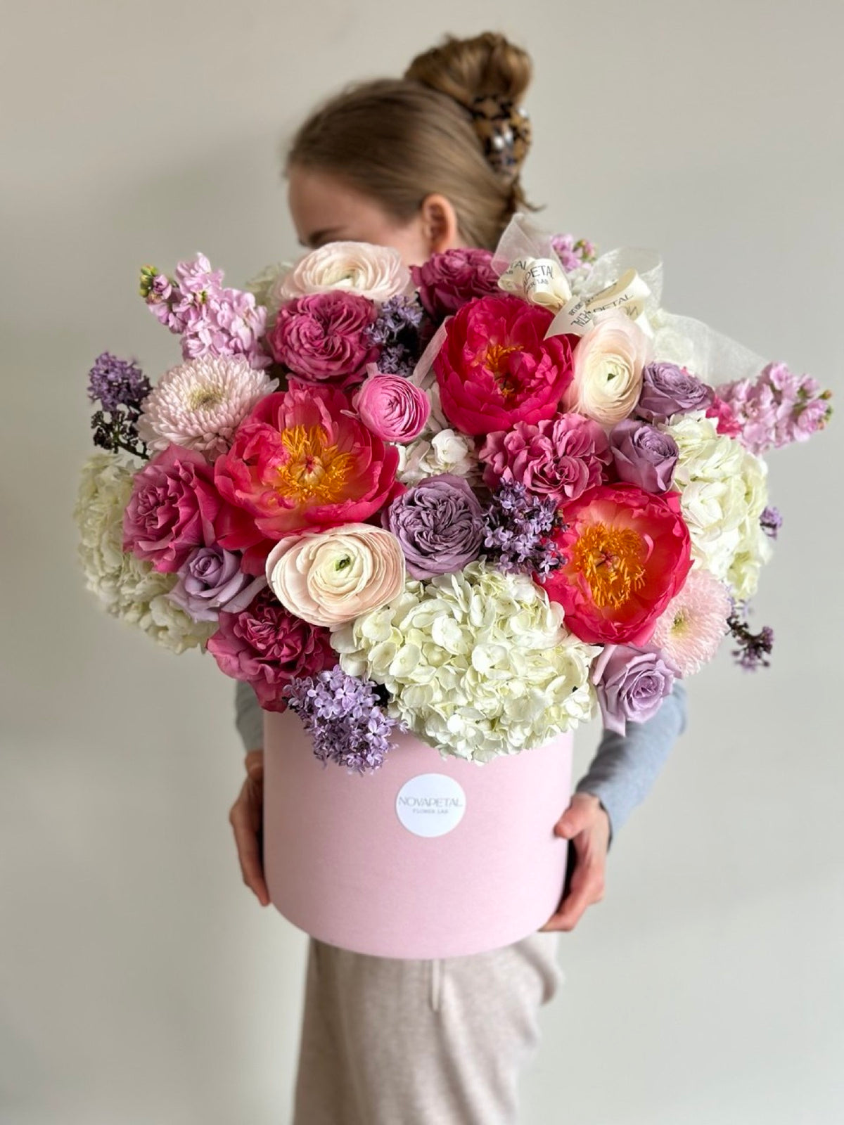 A Lilu hat box of coral charm peonies, garden roses, hydrangea and ranunculus