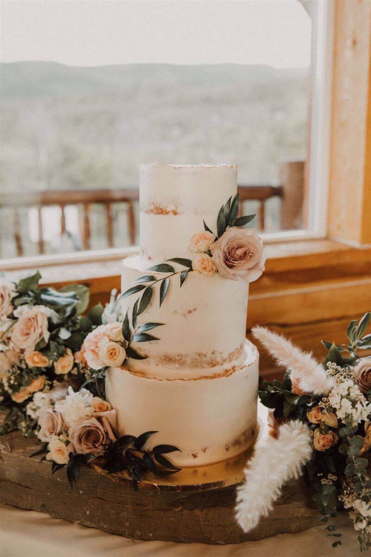 Three-tier semi-naked wedding cake by Novapetal Flower Lab, dressed with mauve roses and pampas grass