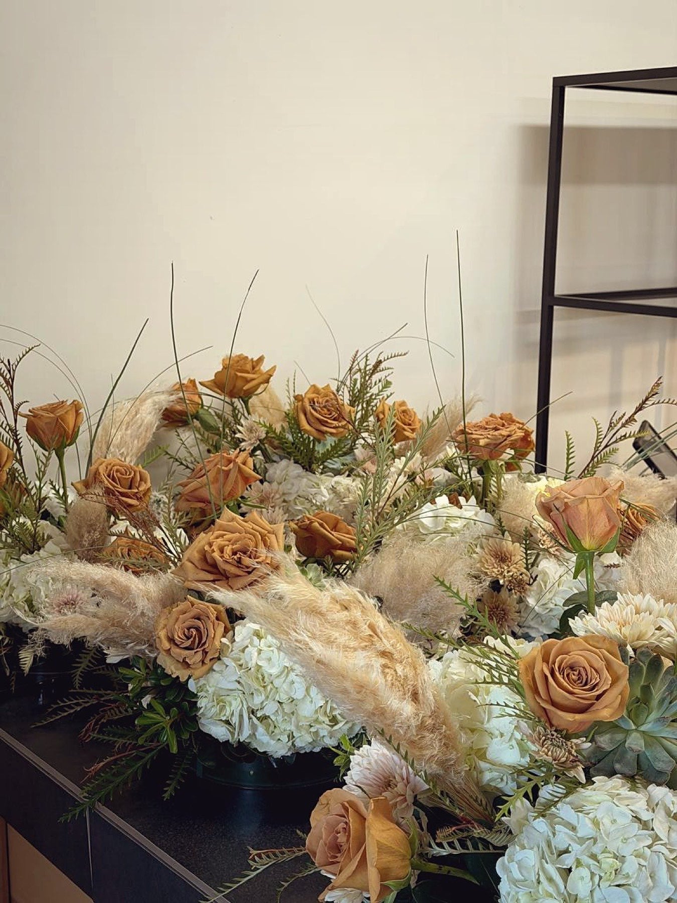 Row of boho centrepieces by Novapetal Flower Lab with toffee roses, pampas and succulents