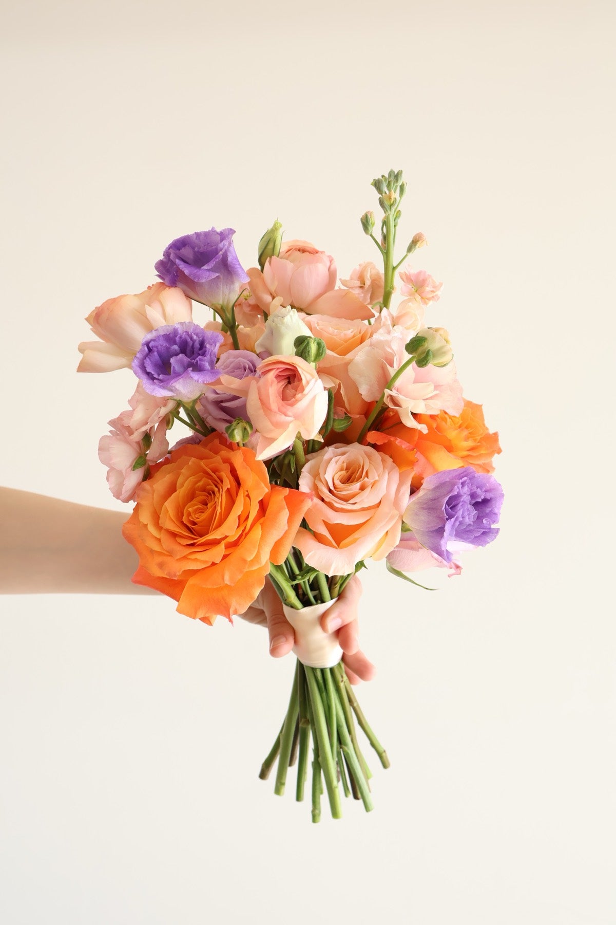Orange and purple bridal bouquet by Novapetal with roses lisianthus and stock