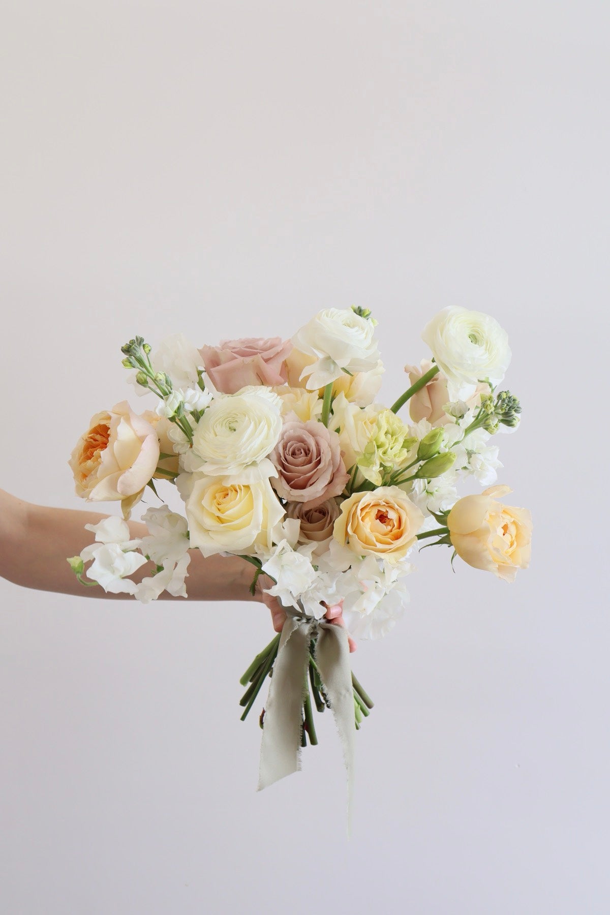 Cream peach and mauve bridal bouquet by Novapetal with garden roses ranunculus and stock