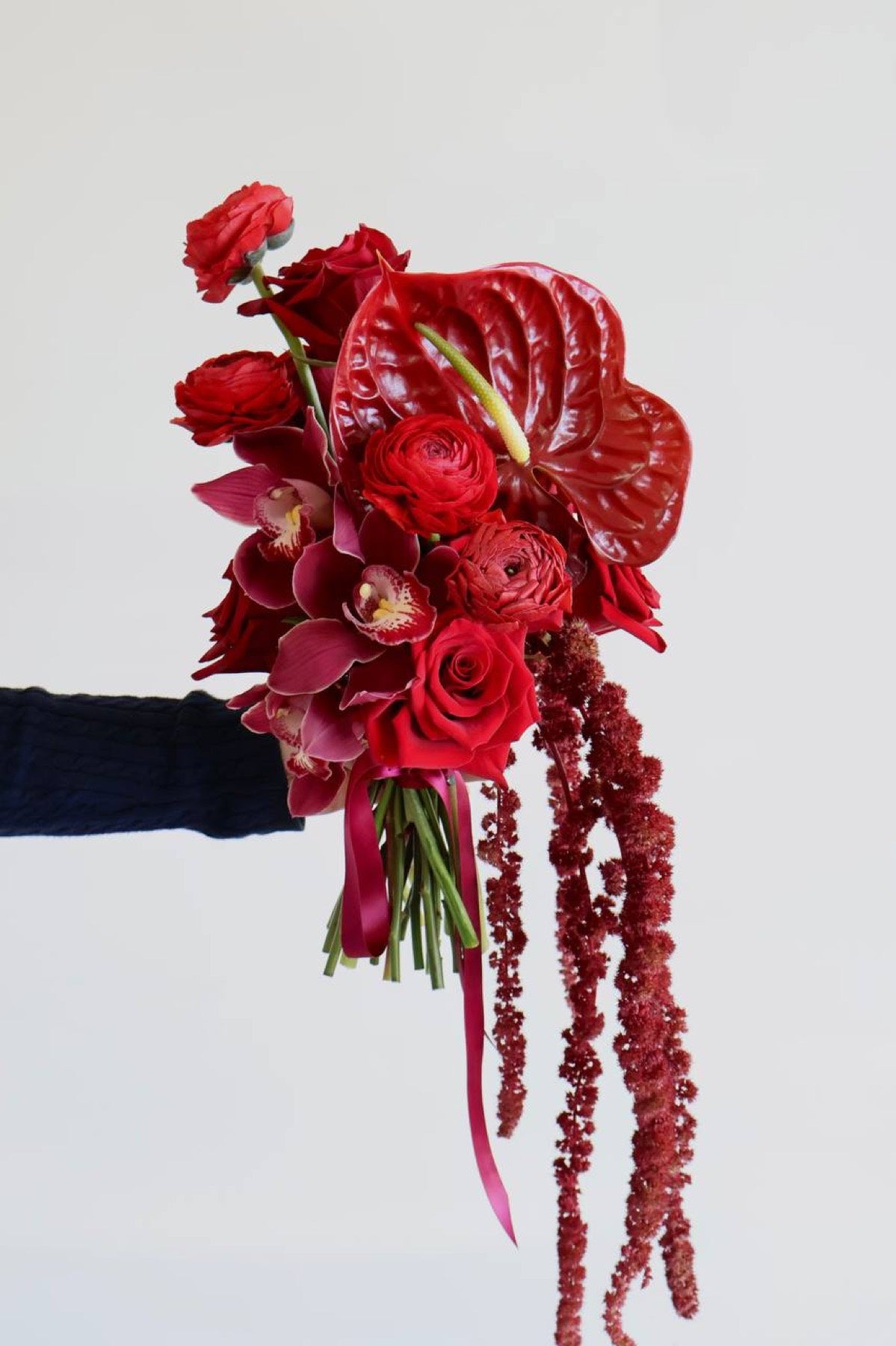 Cascading red bridal bouquet by Novapetal with anthurium cymbidium orchids roses and amaranthus