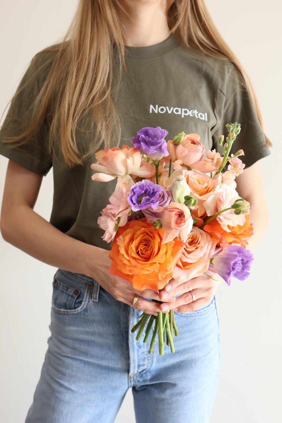 Novapetal florist holding an orange and lilac hand-tied bridal bouquet