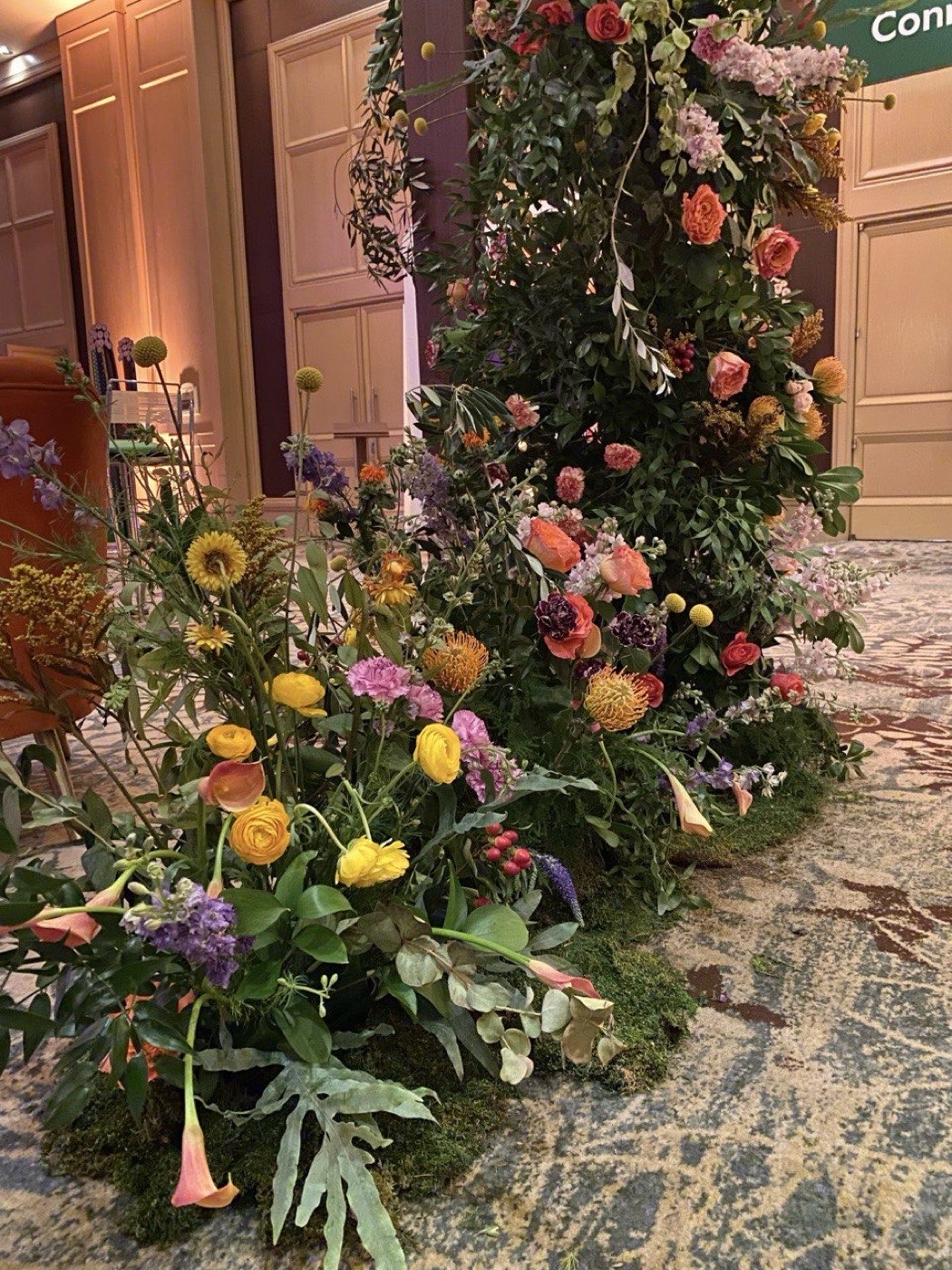 Detail of the ground-level florals by Novapetal Flower Lab at a Fidelity corporate event, with pincushion protea, ranunculus, garden roses, calla lilies and delphinium spilling onto the ballroom floor