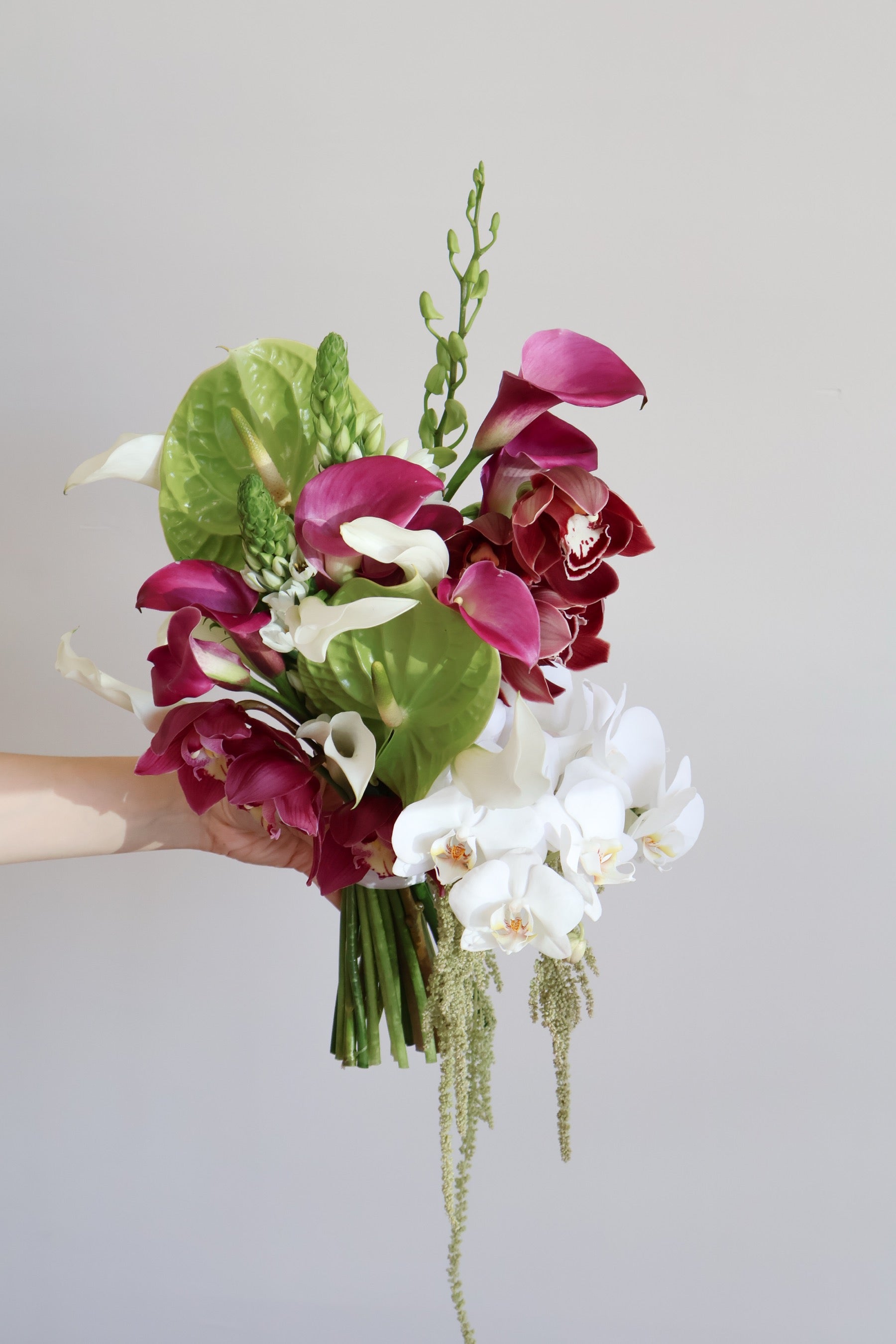 Hand-tied bouquet by Novapetal Flower Lab of green anthurium, magenta calla lilies, burgundy cymbidium and white phalaenopsis orchids