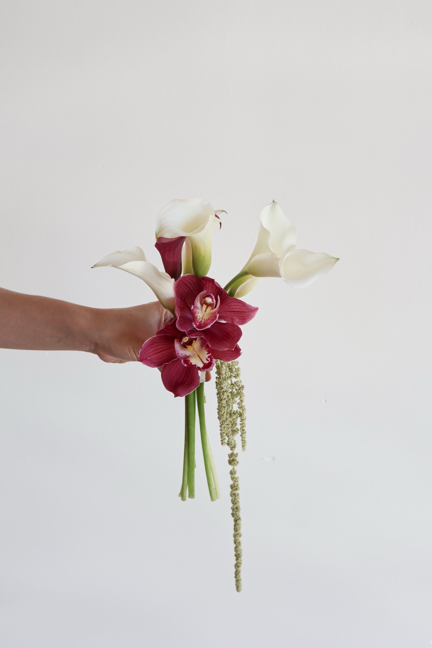 Small bouquet by Novapetal Flower Lab of white and burgundy calla lilies with cymbidium orchids and trailing green amaranthus