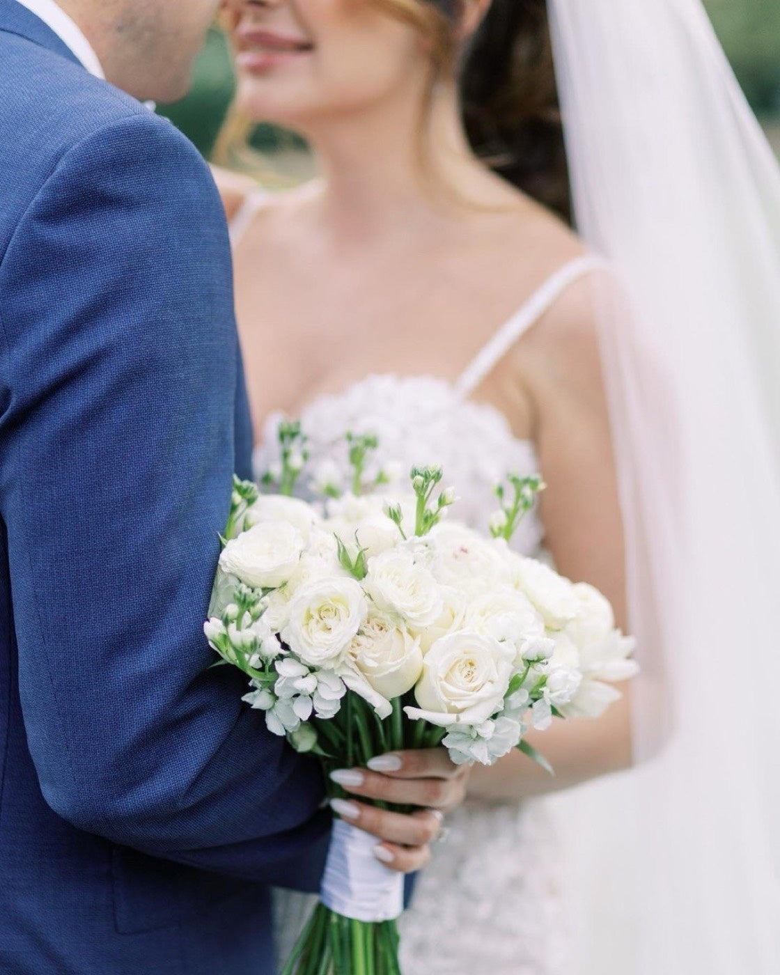 Bride and groom at a Phoenix wedding, the bride holding a white rose and ranunculus bouquet by Novapetal Flower Lab