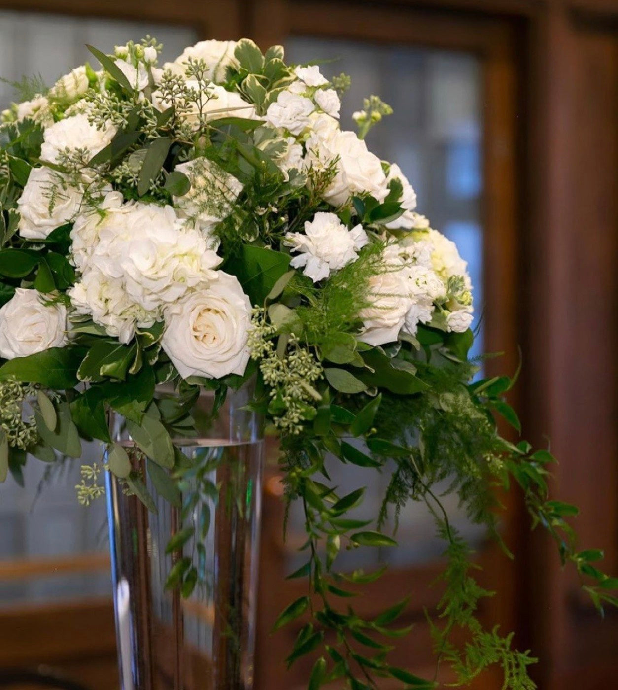 The same tall white arrangement by Novapetal Flower Lab seen closer, with roses, ranunculus and eucalyptus