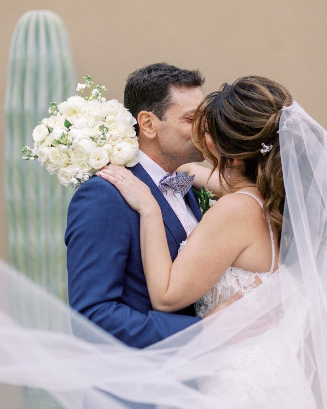 Couple beside a saguaro cactus in Phoenix, the bride holding a white rose and ranunculus bouquet by Novapetal Flower Lab